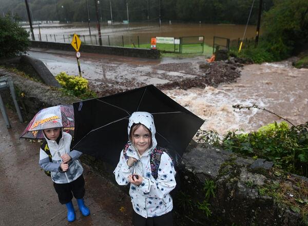 Alys and Zac Lane from Glanmire Co Cork beside the damaged road and flooded Glanmire GAA pitch. Picture: Eddie O'Hare